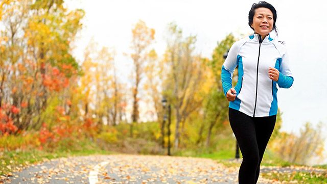 Older woman running outdoors in autumn