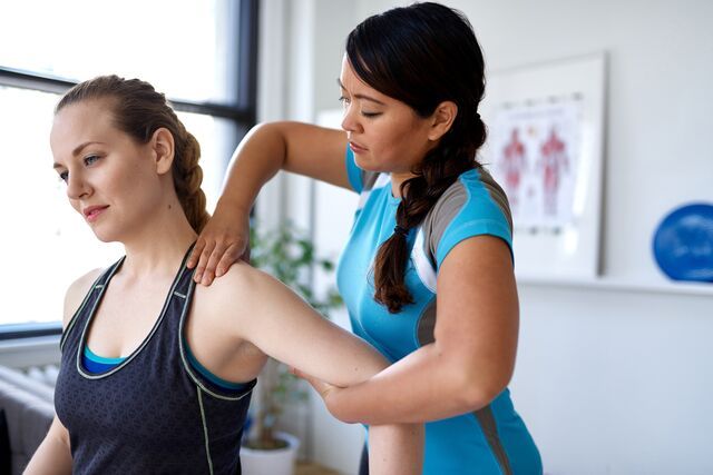 Physiotherapist working with female patient on exercise equipment