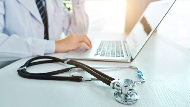 Doctor using a laptop with a stethoscope in the foreground